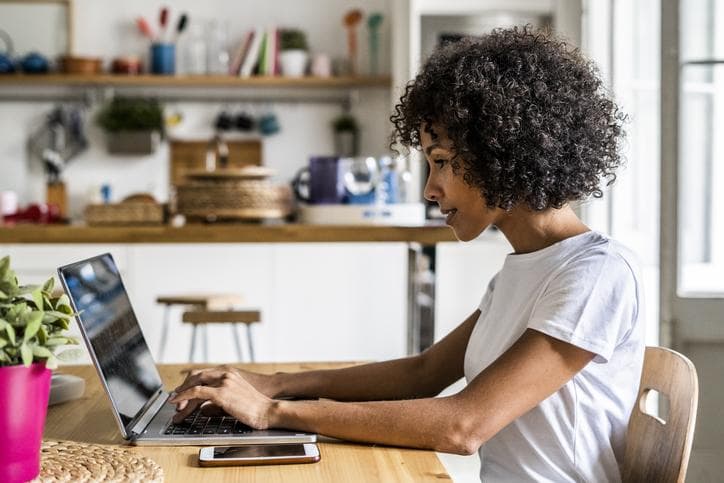 Woman typing on laptop in kitchen