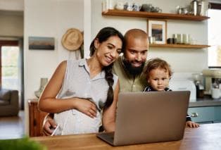 A family of three look at a laptop