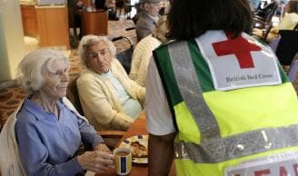 A British Red Cross worker talks to two elderly women.