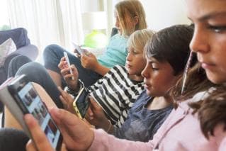 Group of children looking at phones and tablets