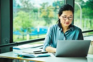 Woman working on laptop by window