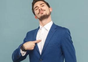 Man in a suit pointing at himself