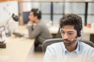 A call handler sits at a desk with a headset