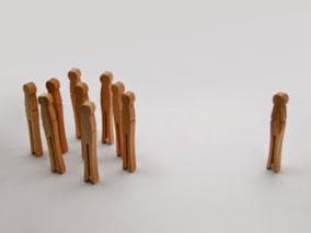 Group of wooden pegs with one peg standing apart