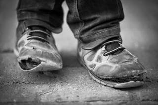 Legs wearing a pair of worn and torn shoes