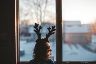 child in antlers looking out of the window