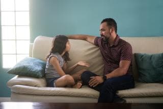 Parent sat on sofa speaking to child