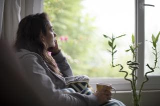 young woman looking sadly out of the window