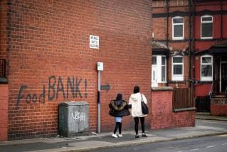 mother and daughter walking past foodbank graffiti