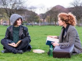 Two young women sat talking outside