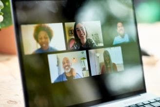 Laptop screen displaying people meeting on a video conferencing call