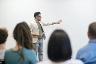 Male teacher in a beige jacket in front of a class