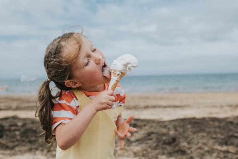 A girl eats an ice cream on the beach.jpg