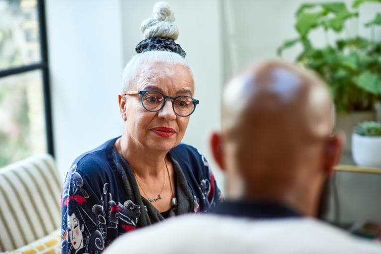 A woman sitting on a sofa talking to a man.