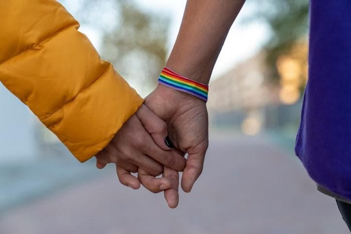 Holding hands wearing a rainbow bracelet