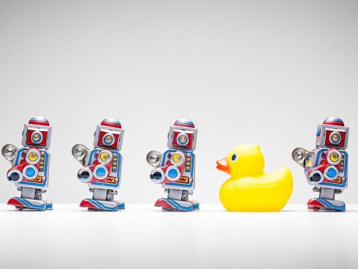 Line of toy robots and one rubber duck