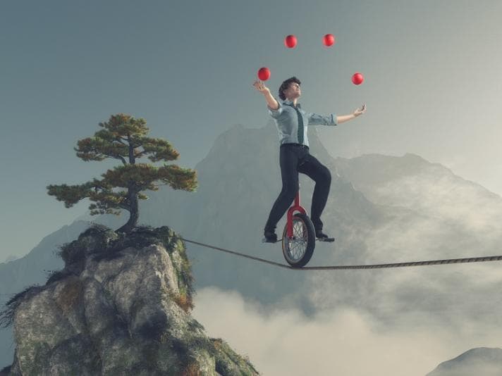 Man unicycling on a tightrope while juggling