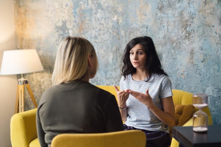 Two women sitting on chairs talking.