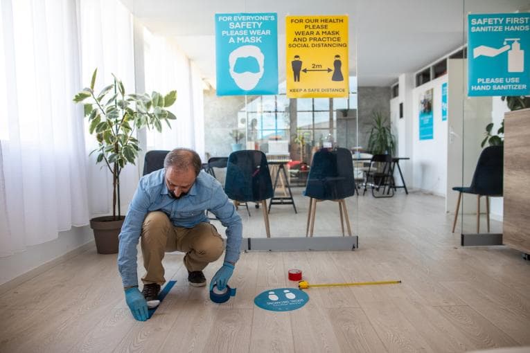 A man marks out social distances on a floor