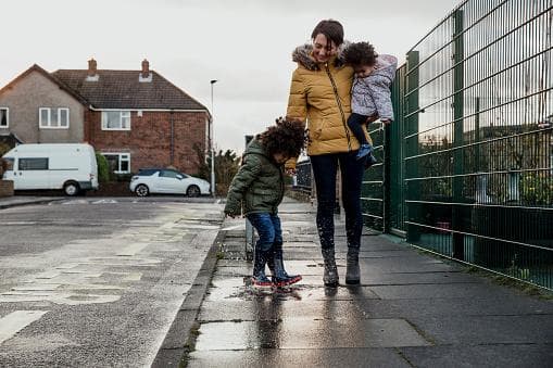 A mother walks down the road with her two young children