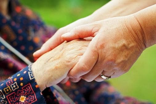 Carer holding an elderly person's hand