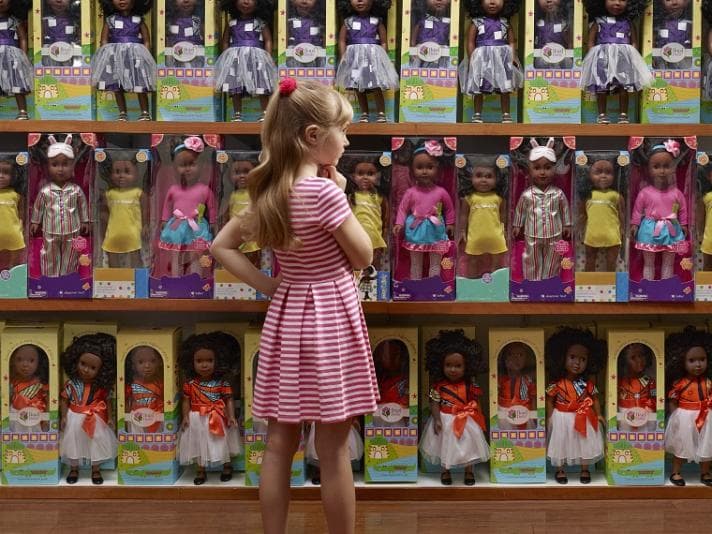 Child in front of shelves full of dolls