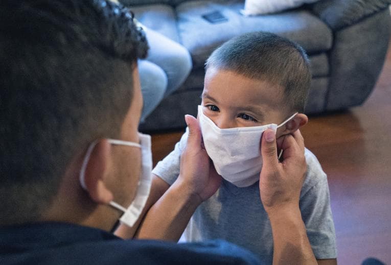 Father putting face mask on his son