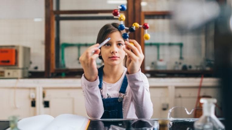 Girl looking at atom structure in science class