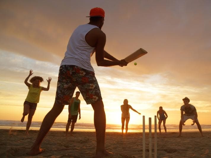 Group of people playing cricket on the beach