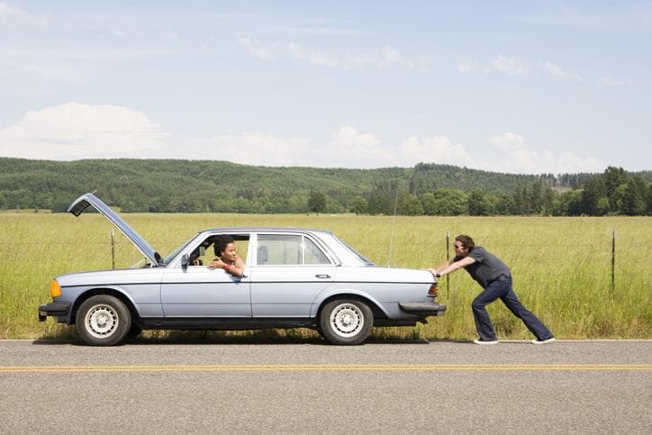 Man pushing broken down car