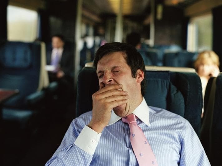 Man stifling a yawn on the train