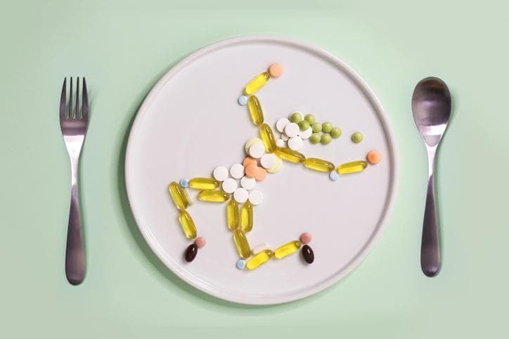 Pills and vitamins on a plate arranged in the shape of a running figure