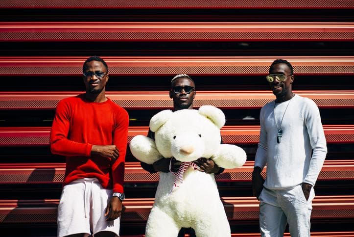 Three cool young men, one holding a large teddy bear