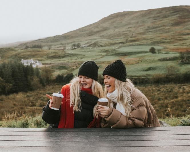 Two women sitting outside in coats and scarves