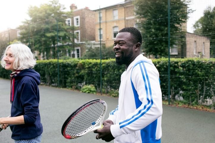 women and man playing tennis outside