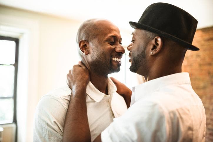 2 men smiling whilst embracing