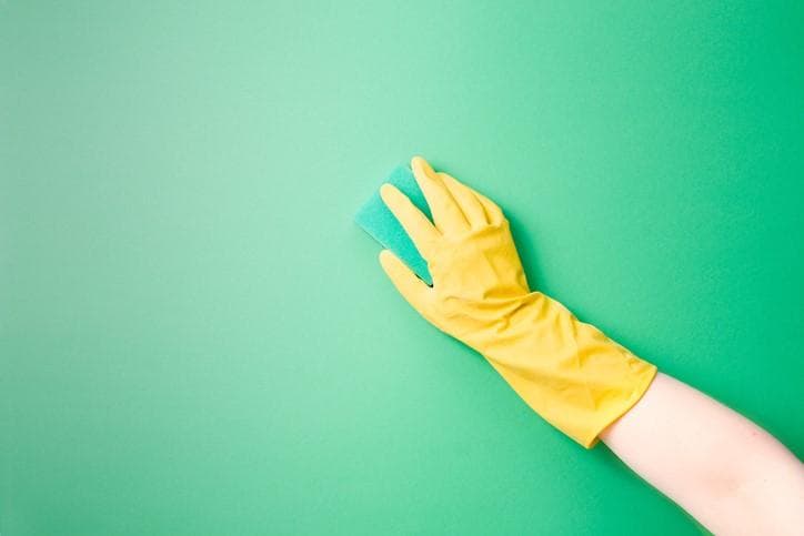 A hand in a yellow glove on a green background