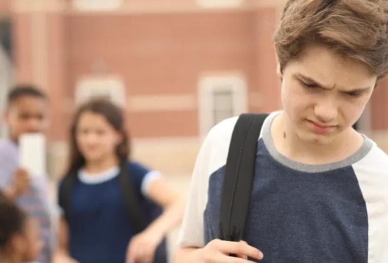 Boy looking upset in front of other teenagers