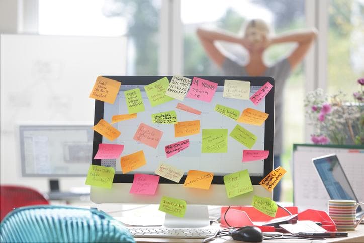 Computer screen covered with sticky note reminders