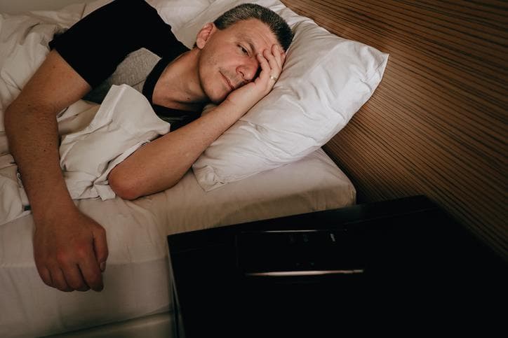 Man in bed struggling to sleep