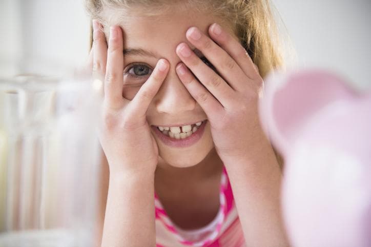 Smiling girl with hands over her eyes