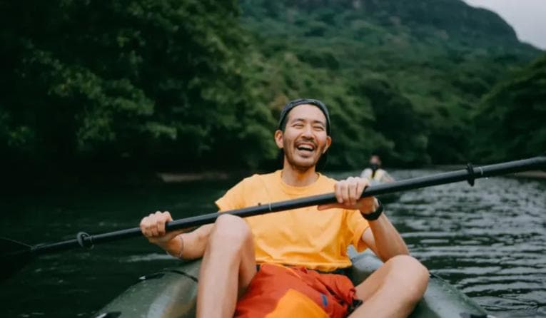 Smiling man paddling a canoe down a river