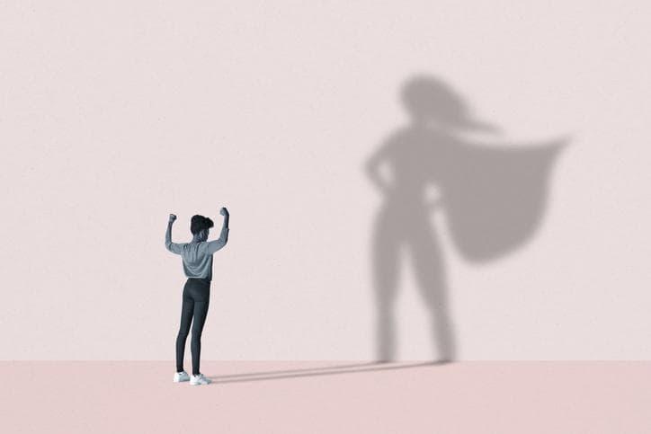 Woman flexing in front of superhero shadow