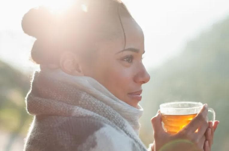 Woman holding warm cup of drink