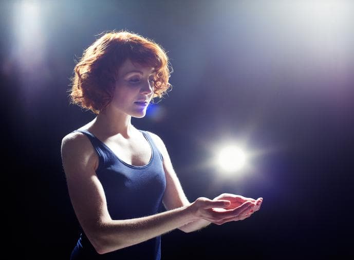 Woman in dark room holding a beam of light