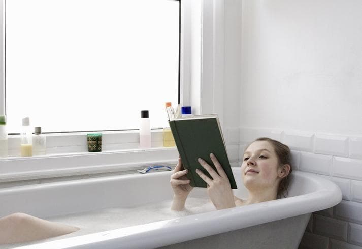 Woman reading a book in the bath