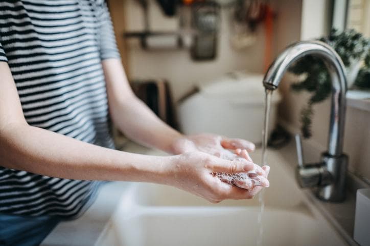 Woman washing hands at kitchen sink