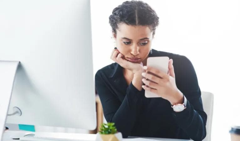 Bored woman looking at her phone at work