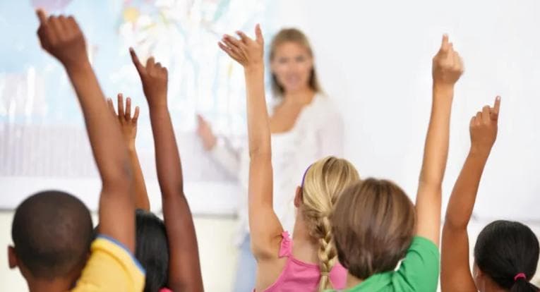 Class of children raising their hands