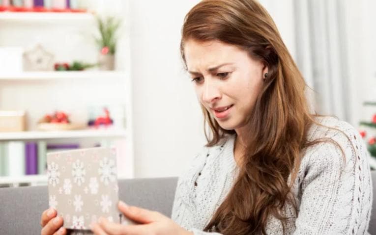 Confused woman opening gift